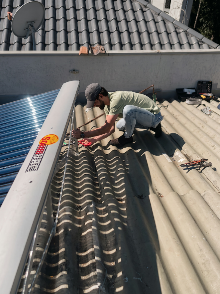 Técnico da Agás instalando coletor solar no telhado